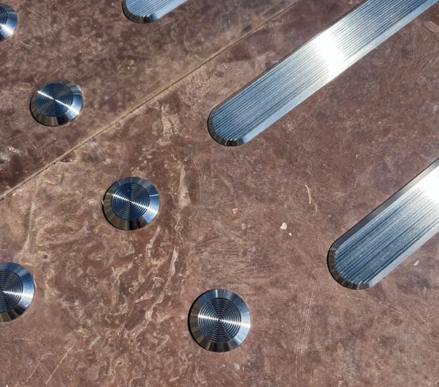 Taktila ledstavar och stoppmarkeringar i rostfritt stål på brunt stengolv