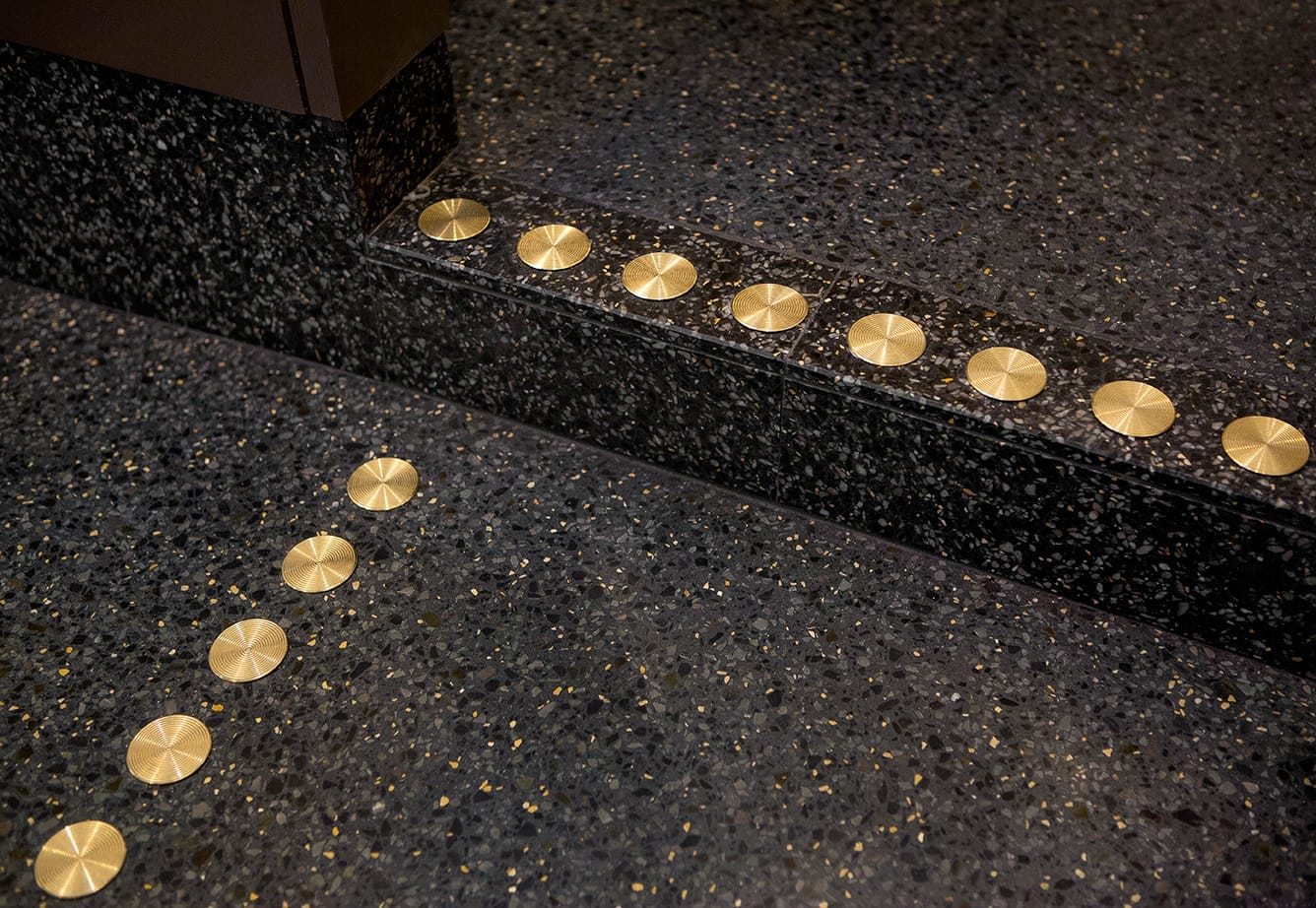 Kontrastmarkering mässing på mörkt stengolv