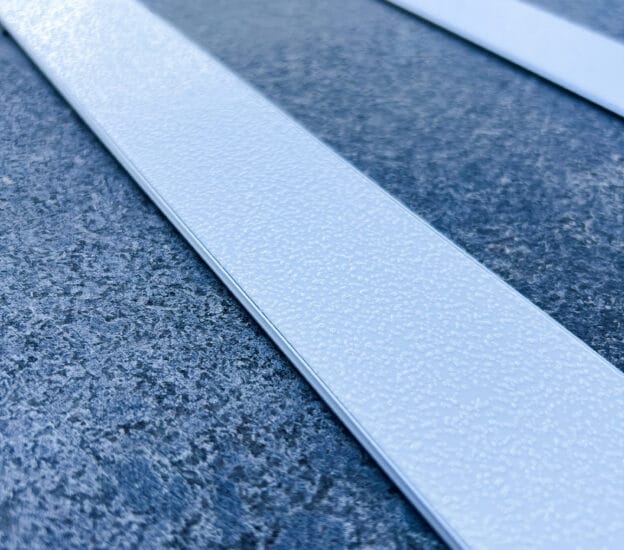 Vit aluminiumlist med vitt halksäkert ilägg på grått stengolv